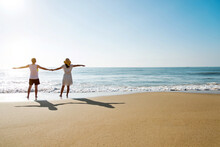 Young Couple Embracing Enjoying Ocean On Beach.