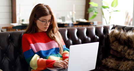 Young woman working remotely behind a laptop, home office.