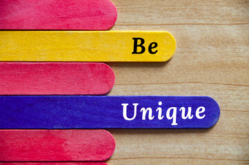 Be unique text on colorful wooden stick. Motivational and inspirational concept.