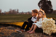 © Myroslava - The little joyful children with big bouquet roses, siting together outdoors