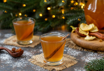 Uzvar drink. Ukrainian Winter Punch or Dried Fruit Compote served in two glasses with dried fruits and pitcher on a table. Holiday concept, yellow lights of the New Year's eve on background.