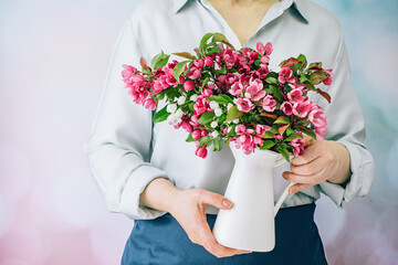 Wall Mural - Hands of woman florist in apron holds a bunch of magenta pink spring flowers. Midsection. No face. Springtime gardening. Mothers day. Bouquet of viva flowers on blue Copy space.