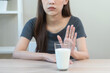 © KMPZZZ - Allergy asian young woman, girl hand in deny, no or push out to avoid for drink milk at home, unhappy and bad stomach ache. Lactose intolerance and dairy food, health problem, belly suffer concept.