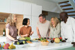 © PhotoAlto - Diverse group of senior friends gathered at kitchen counter while drinking wine