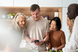 © PhotoAlto - Diverse group of senior friends stading in the kitchen while checking recipe on cell phone