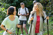 © PhotoAlto - Two middle-aged ladies with hiking poles walking in the woods with their partners behind them