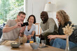 © PhotoAlto - Senior man sharing pictures on smart phone with friends while sitting on sofa