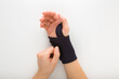 Young adult woman hand putting protective black elastic wrist bandage on white table background. Closeup. Point of view shot. Top down view.