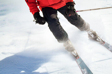 Close up male skier bottom view of ski boots and skis while stop on carving in fast motion