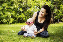 Portrait Of A Young Mother Spending Quality Time With Her Daughter In A Park During The Summer And The Baby Is Wearing Funny Sunglasses; Edmonton, Alberta, Canada