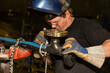 © Designpics - Pipe fitter inspects tack welds with a flashlight before butt welding a flange to a pipe in a metal fabrication plant; Innisfail, Alberta, Canada