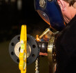 © Designpics - Pipe fitter is tack welding a flange assembly to pipe using a level in a metal fabrication plant; Innisfail, Alberta, Canada