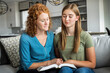 © Designpics - Mother and teenage daughter sitting on a couch at home reading the Bible and praying together; Edmonton, Alberta, Canada