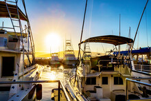 View Through Yachts And Sailboats Moored In A Harbor Marina In Lahaina With The Golden Sun Setting Behind; Lahaina, Maui, Hawaii, United States Of America