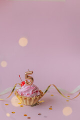 a beautiful picture of a cupcake with pink butter cream and cherry with a number five 5 candle on the top of it. Festive Happy birthday mood. Card design idea. 