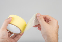 Paper Adhesive Tape Isolated On White. A Roll Of Paper Duct Tape In The Hands Of A White Man. Unfolded Adhesive Tape With Space For Text.