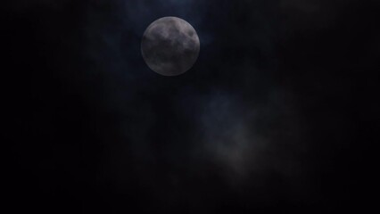 big full moon with dark, eerie clouds drifting past, at night.