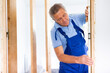 © JackF - Man builder in blue overalls measures deviations from a given vertical wall using a building level