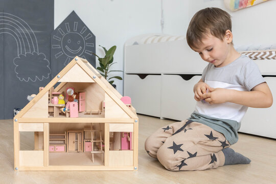 Non binary diverse male kid playing wooden dolls house enjoy happy childhood at home room interior