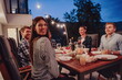 © .shock - A group of young diverse people having dinner on the terrace of a modern house in the evening. Fun for friends and family. Celebration of holidays, weddings with barbecue.