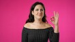 © Robert Peak - Portrait of attractive young hipster woman 20s giving okay gesture smiling happy isolated on pink background studio portrait with copy space