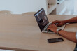 © .shock - African American man in glasses sitting at a table in a modern living room, using a laptop for business video chat, conversation with friends and entertainment