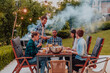 © .shock - A group of young diverse people having dinner on the terrace of a modern house in the evening. Fun for friends and family. Celebration of holidays, weddings with barbecue.