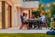 © .shock - A group of young diverse people having dinner on the terrace of a modern house in the evening. Fun for friends and family. Celebration of holidays, weddings with barbecue.