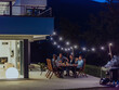 © .shock - A group of young diverse people having dinner on the terrace of a modern house in the evening. Fun for friends and family. Celebration of holidays, weddings with barbecue.