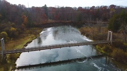 Wall Mural - Aerial right up to suspension bridge over river in Michigan with late fall vibes