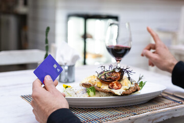 paying with credit card on a restaurant with the credit card on one hand and holding a finger up