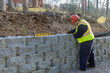 © ungvar - Man leveling tool building retaining concrete block wall with being built on new property
