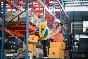 asian warehouse workers or engineer man and woman lifting box of goods to place on the shelf and sta