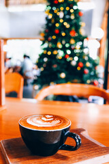 Sticker - Warm cup of coffee on background of christmas tree with lights.