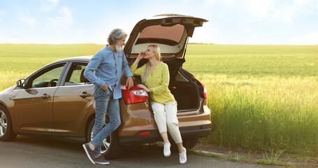 Wall Mural - Happy mature couple near car in countryside