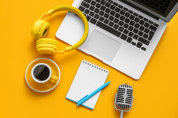 Wall Mural - Notebook with coffee cup, microphone, headphones and laptop on orange background. Podcast concept