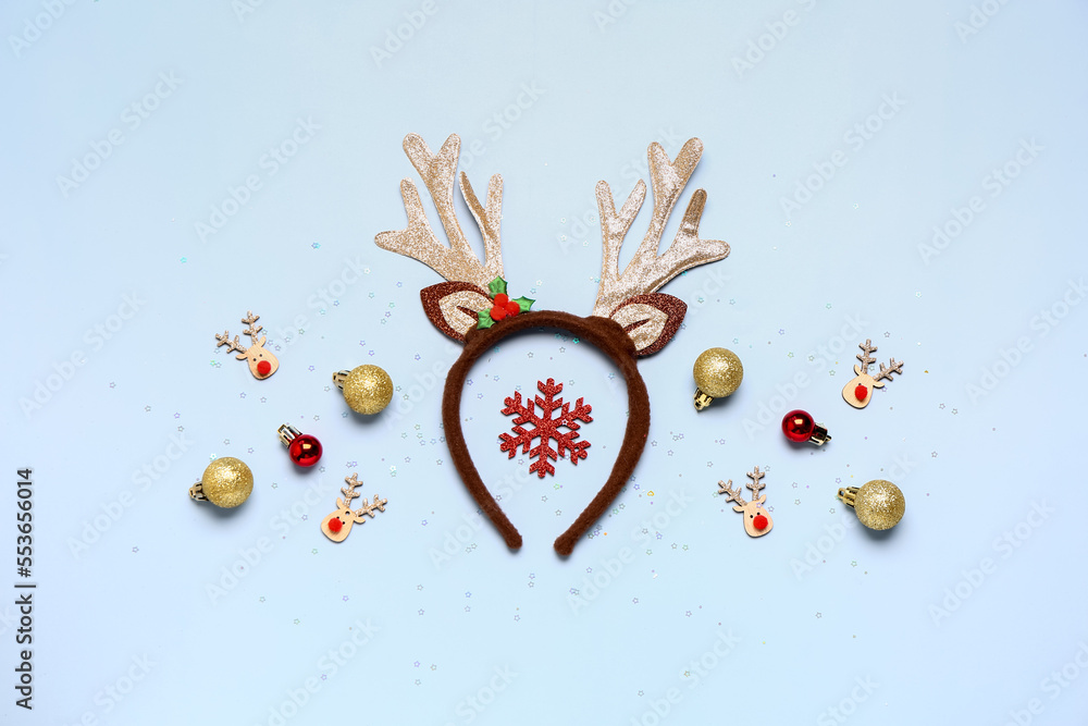 Composition with Christmas reindeer horns and beautiful decorations on light blue background