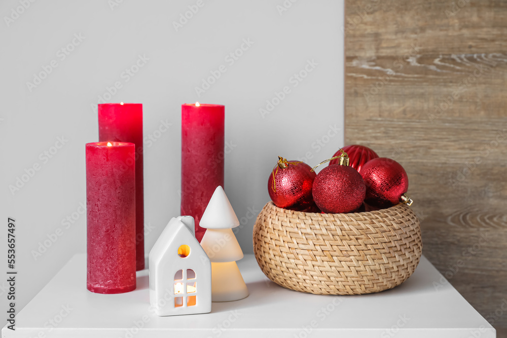 Basket with Christmas balls and candles on table in bedroom