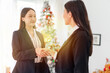 © StockPhotoRepublic - Two young smart beautiful asian lady businesswomen smiling and have a hand shake to commemorate a deal successful in a meeting room in front a Christmas tree