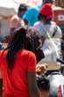 Scenes from the Haitian market near the border with Haiti. Unrecognizable Haitian woman from behind carrying with afro rasta hair looking at some goods in a vendor's stall.