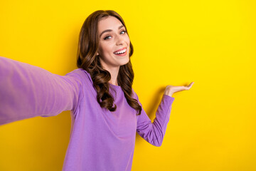 Poster - Closeup selfie photo of adorable excited smiling lady wear purple jumper hold palm demonstrate new product sale isolated on yellow color background