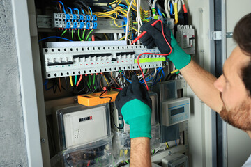 Sticker - Electrician checking electric current with multimeter indoors, closeup