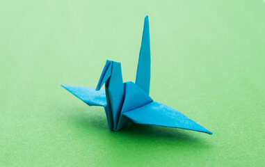 Wall Mural - Blue origami paper crane on green background