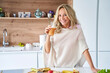 © PhotoAlto - Blonde middle-aged woman enjoying fruit juice at home