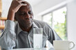 © PhotoAlto - Middle-aged African-American man with headache taking his medicine