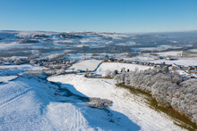 Aerial Drone Photo Of The Town Of Mereclough In The Town Of Burnley In Lancashire, England Showing The Farmers Fields On A Snowy Winters Day In The UK With Snow Covering The Fields And A Blue Sky.