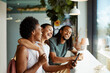 © Flamingo Images - Group of laughing friends looking at cellphone photos over coffee