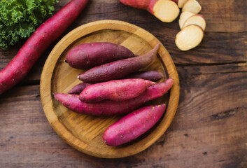 sweet potato tubers on a wooden surface close-up, organic sweet potato