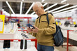 © caftor - elderly man examines tablet computer in showroom of electronics store