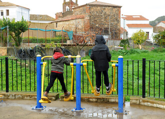 D os niños jugando en el balancín de un parque gimnástico a las afueras del pueblo